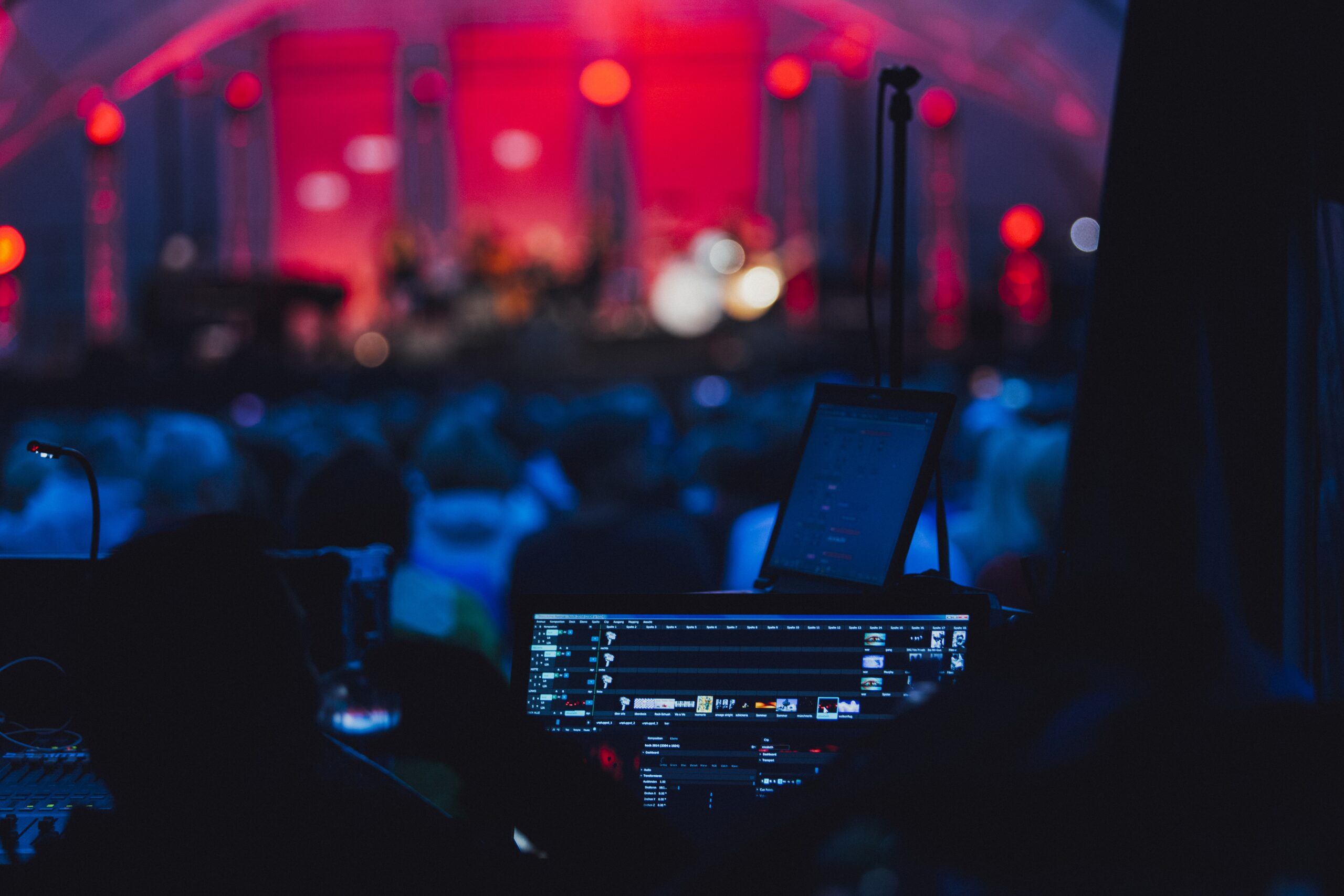 A horizontal shot of a party with lights, a stage and a turned-on computer for the DJ in a club