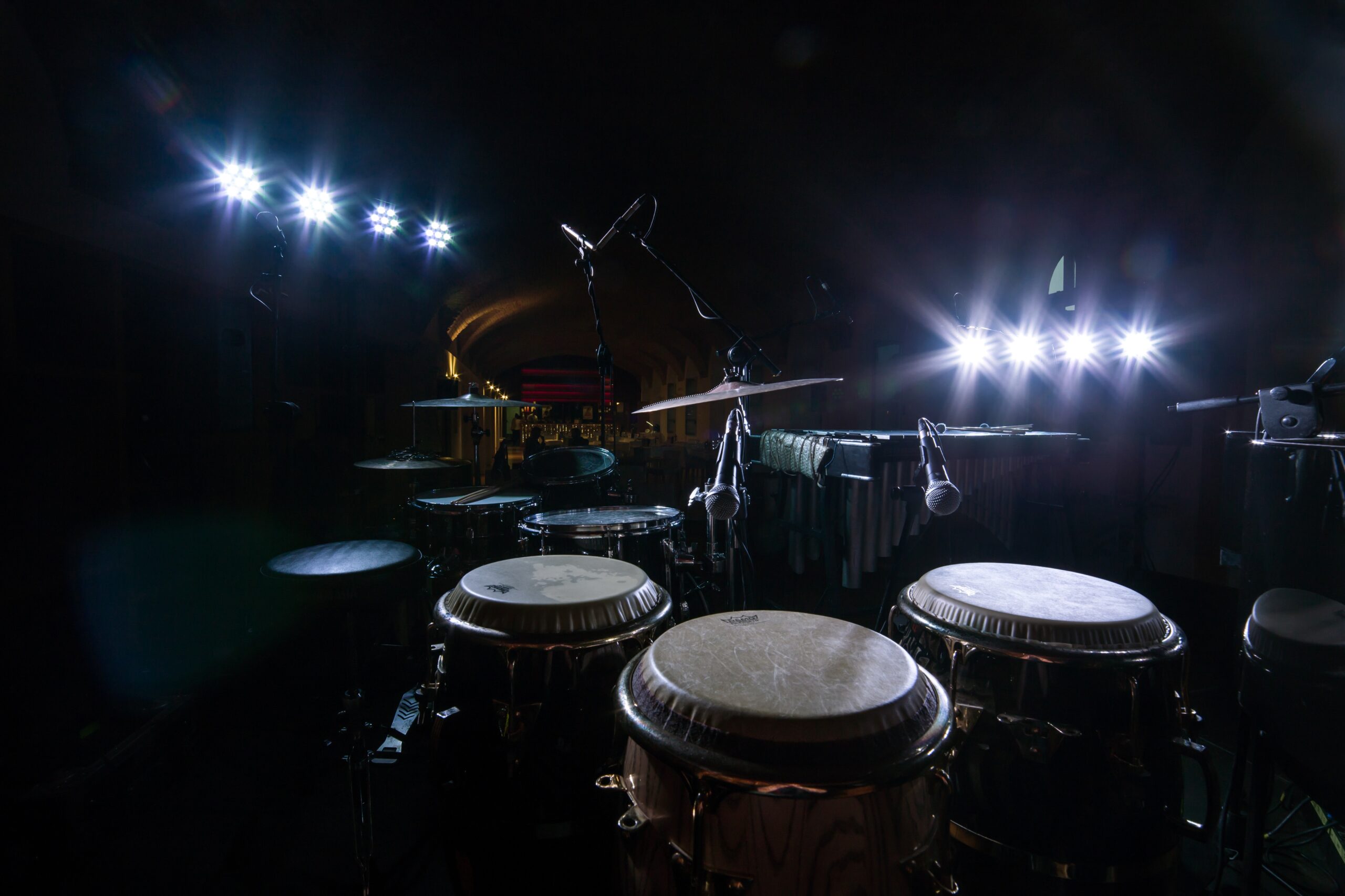 A landscape shot of an old drum set with white spotlights in the background